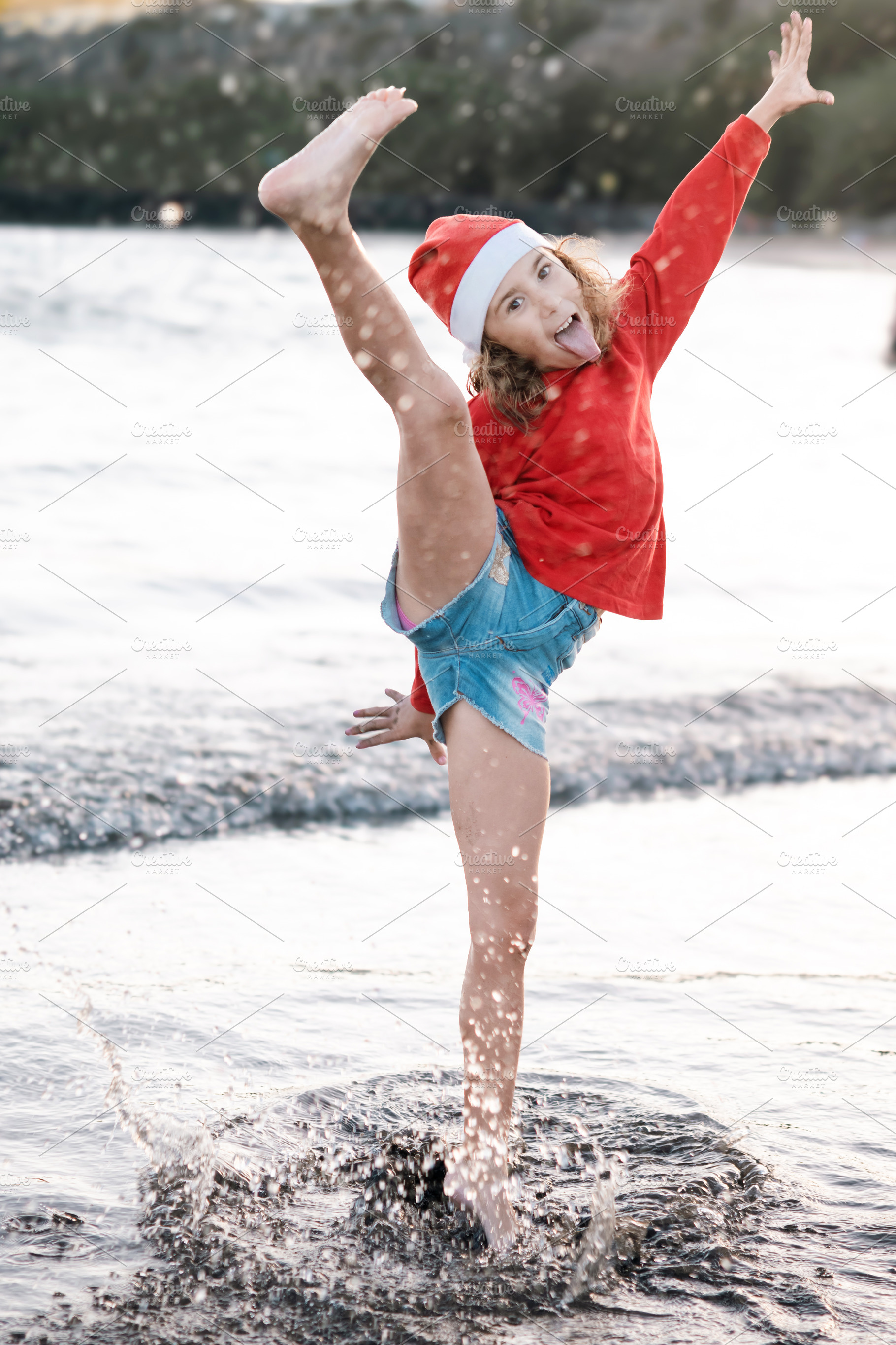 Happy girl in Santa hat playing at the beach during Christmas, a Person Photo by etorres69