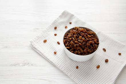 Dried Brown Raisins in a Gray Bowl, side view. Copy space., a Food & Drink Photo by LiudmylaChuhunova