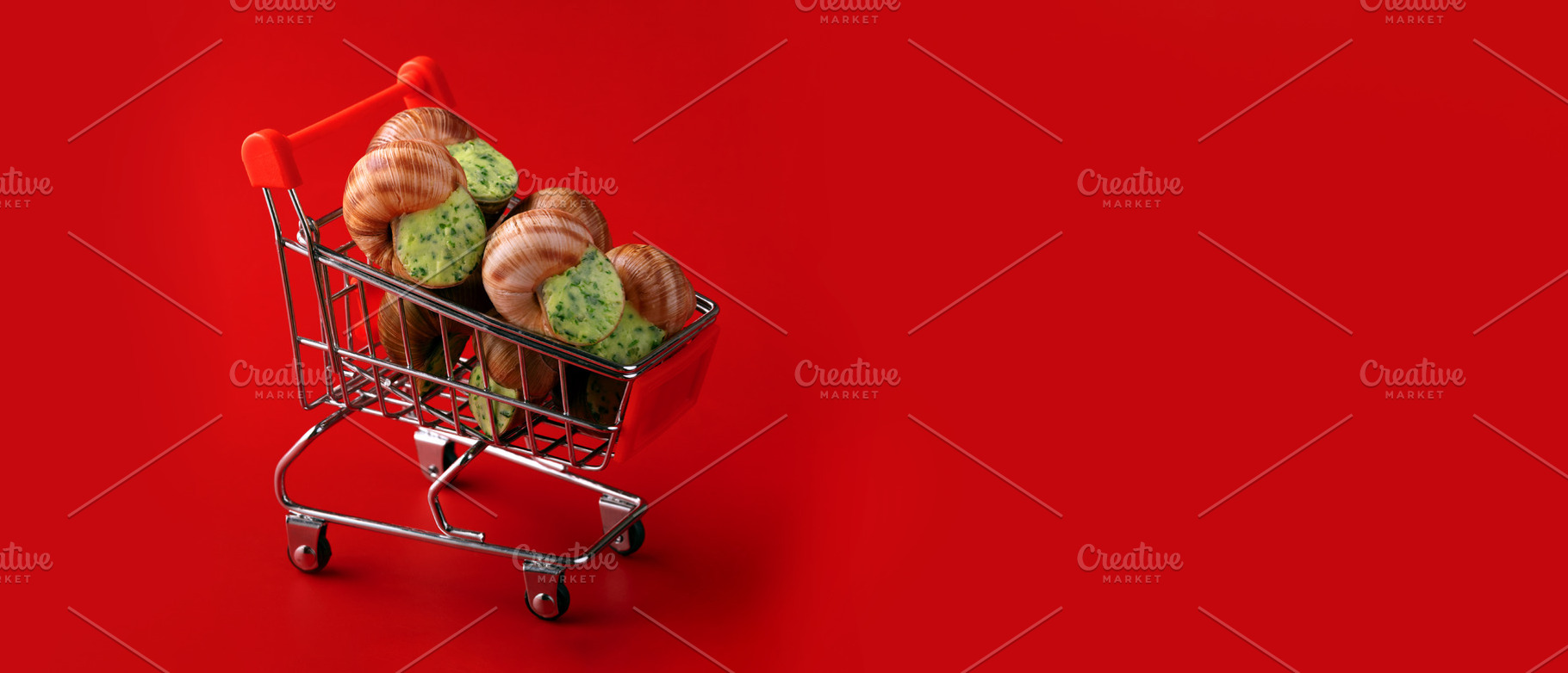 Miniature shopping cart filled with snails against a bold red ba, a Food & Drink Photo by Ales Munt