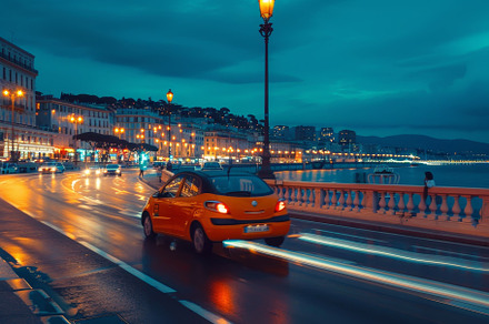 A vibrant orange car drives along a, a Photo by Tanuart