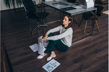 Weary woman sitting on the floor, a Business Photo by undrey