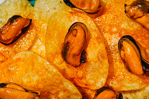 textured close-up of mussels on potato chips, a Photo by Nito