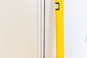 Construction worker using spirit level during door installation, an Architecture Photo by Antonio Gravante Market