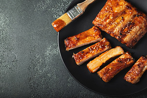 Hot grilled spare ribs from a summer BBQ served on a plate with sauce. Top view, a Food & Drink Photo by Budarinphoto