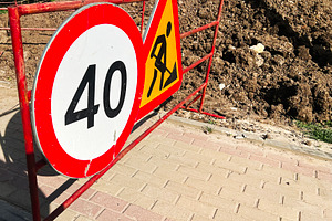 Roadside construction sign indicating speed limit near freshly dug soil, a Photo by AS photostudio