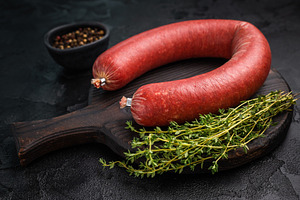 Raw Turkish sucuk (sujuk) on a dark rustic board with fresh thym, a Photo by composter-box@mail.ru