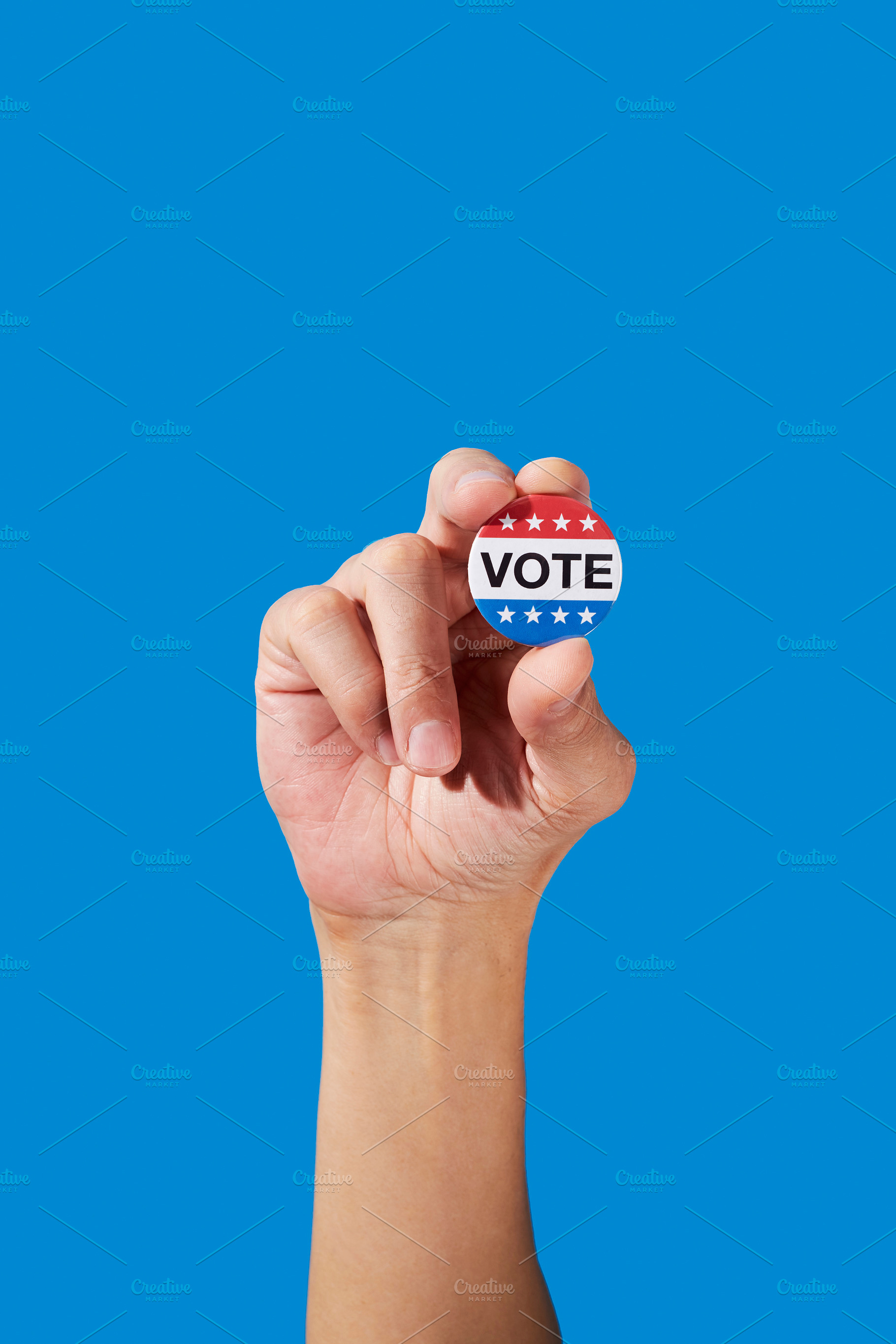 a man holds a vote badge between his fingers, a Photo by Nito