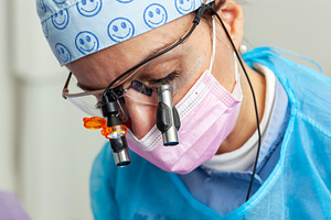 Dentist wearing magnifying glasses and surgical mask performing dental examinat, a Photo by Antonio Gravante Market