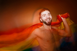 Happy man celebrating lgbtq pride with rainbow flag, a Photo by karrastock