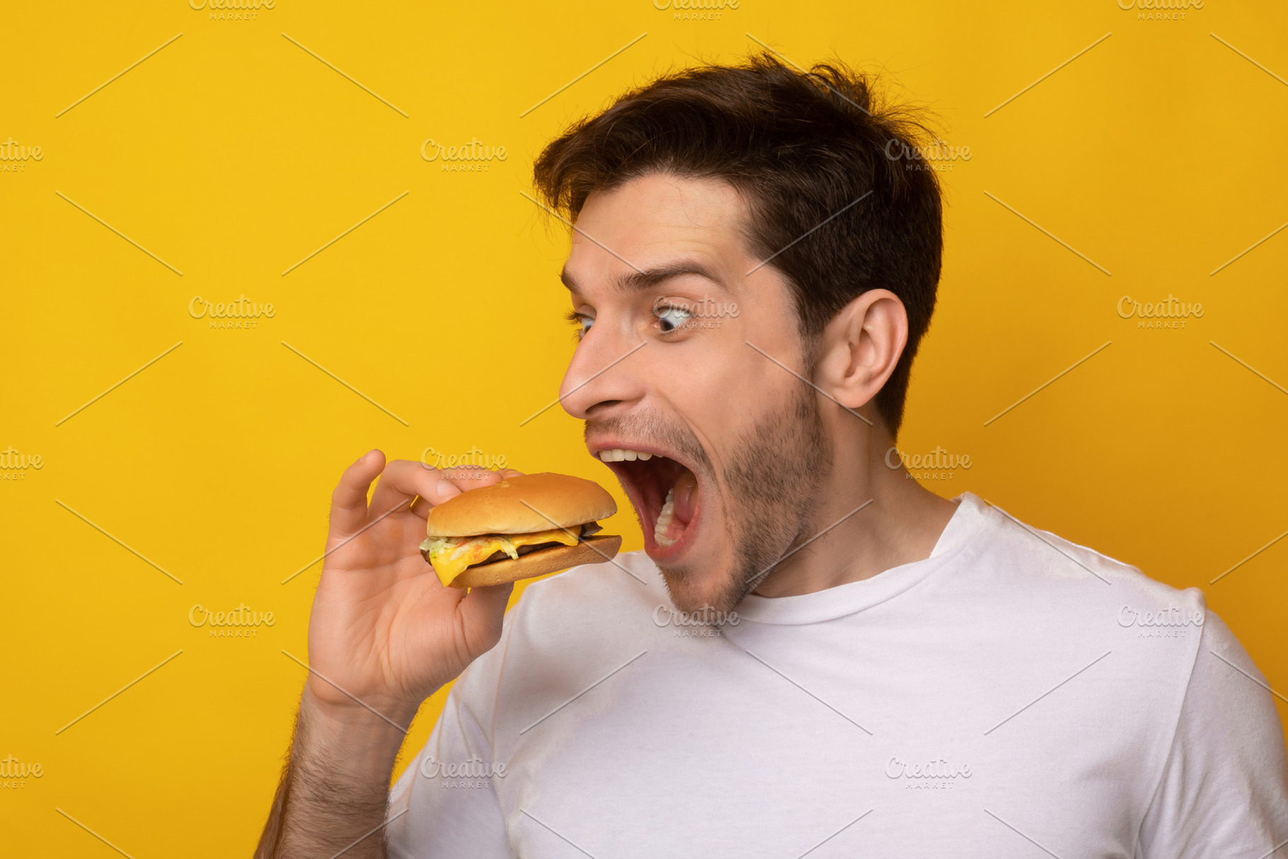 Funny Guy Holding Burger Biting Sandwich At Studio, a Photo by Prostock-Studio