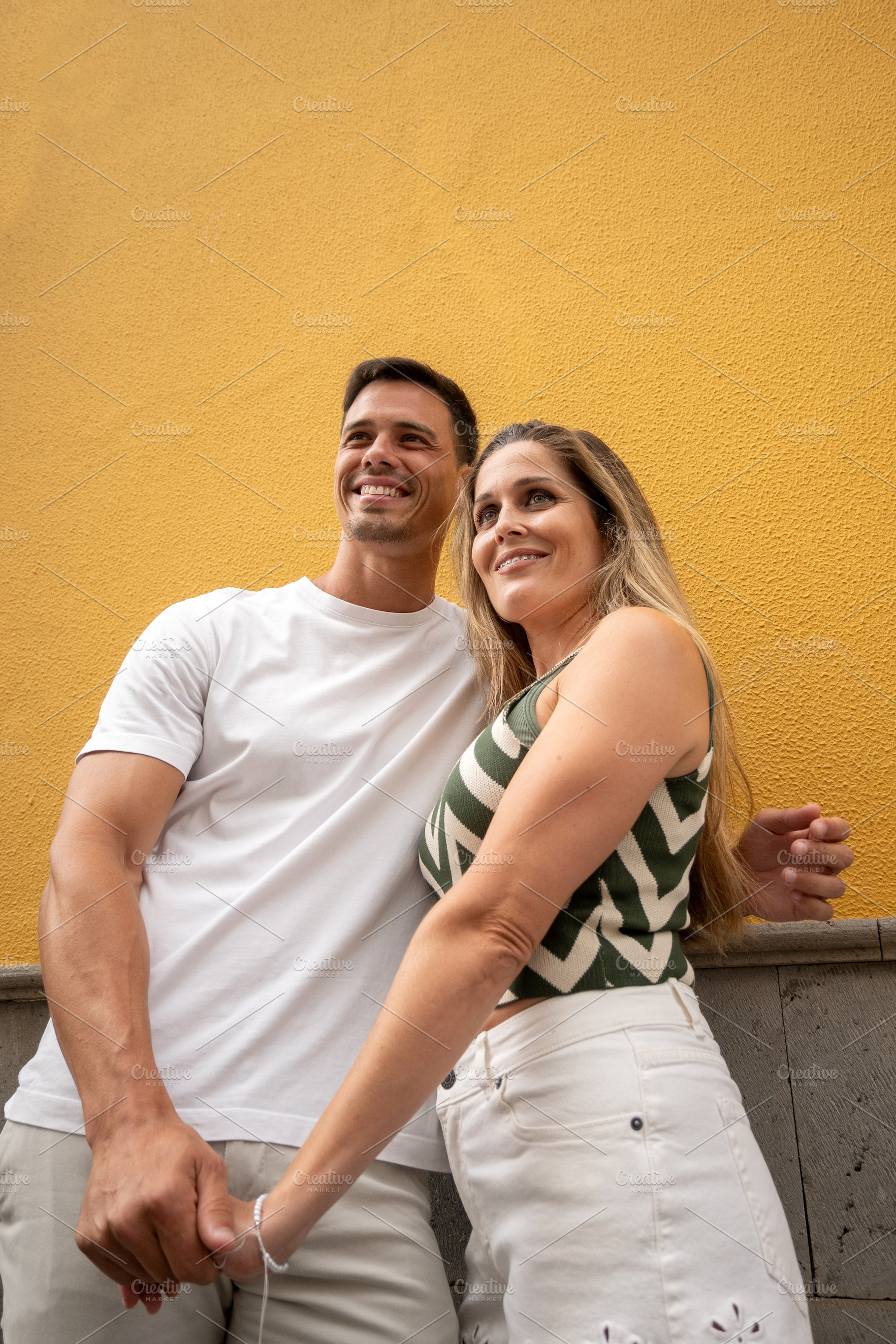 Happy couple holding hands against colorful yellow wall, a Food & Drink Photo by etorres69