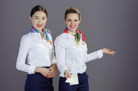 happy elegant female flight attendants isolated on grey, a Business Photo by Alliance Images