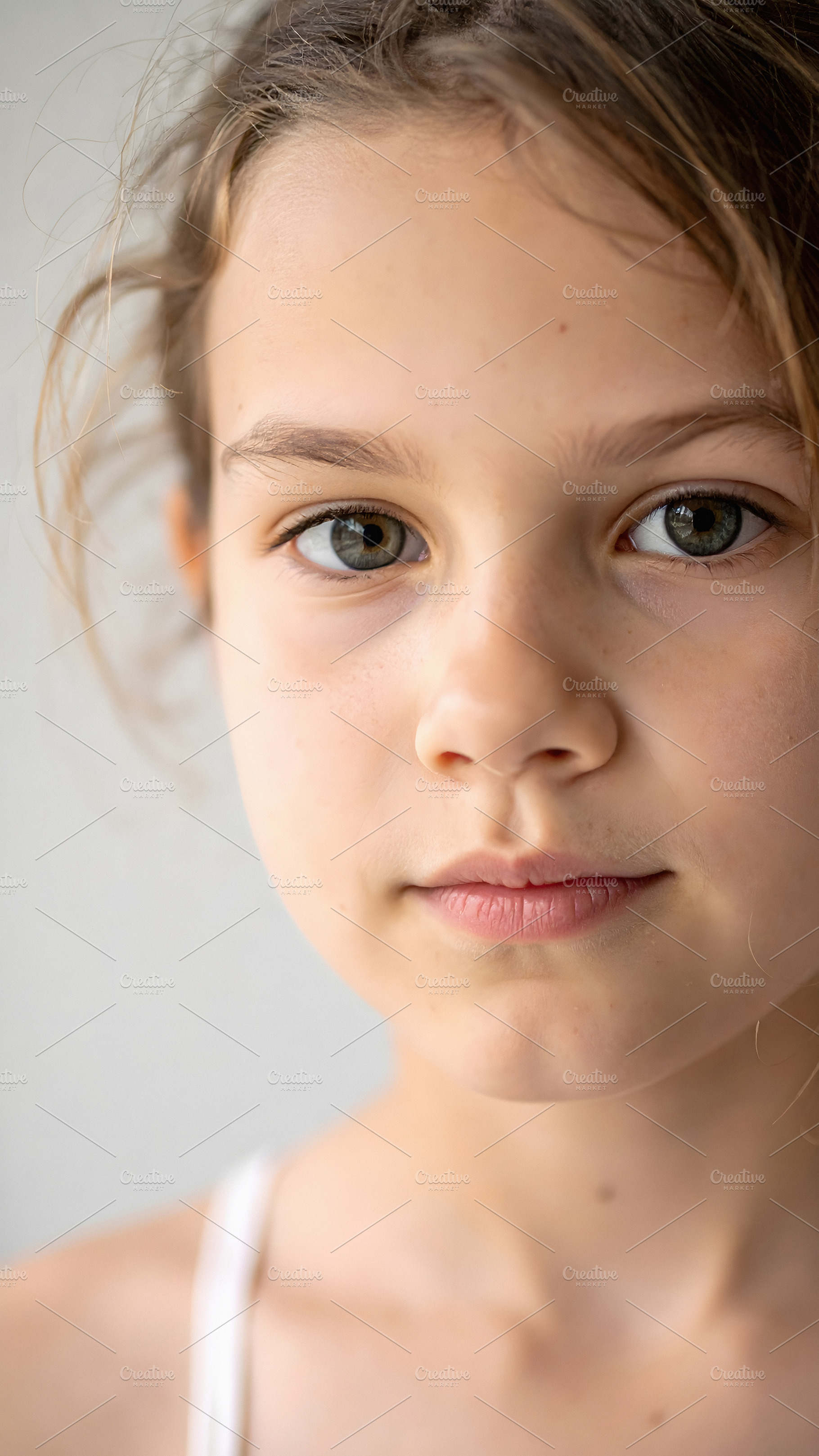 Young girl with light eyes gazing directly into camera, a Person Photo by GoodGoods