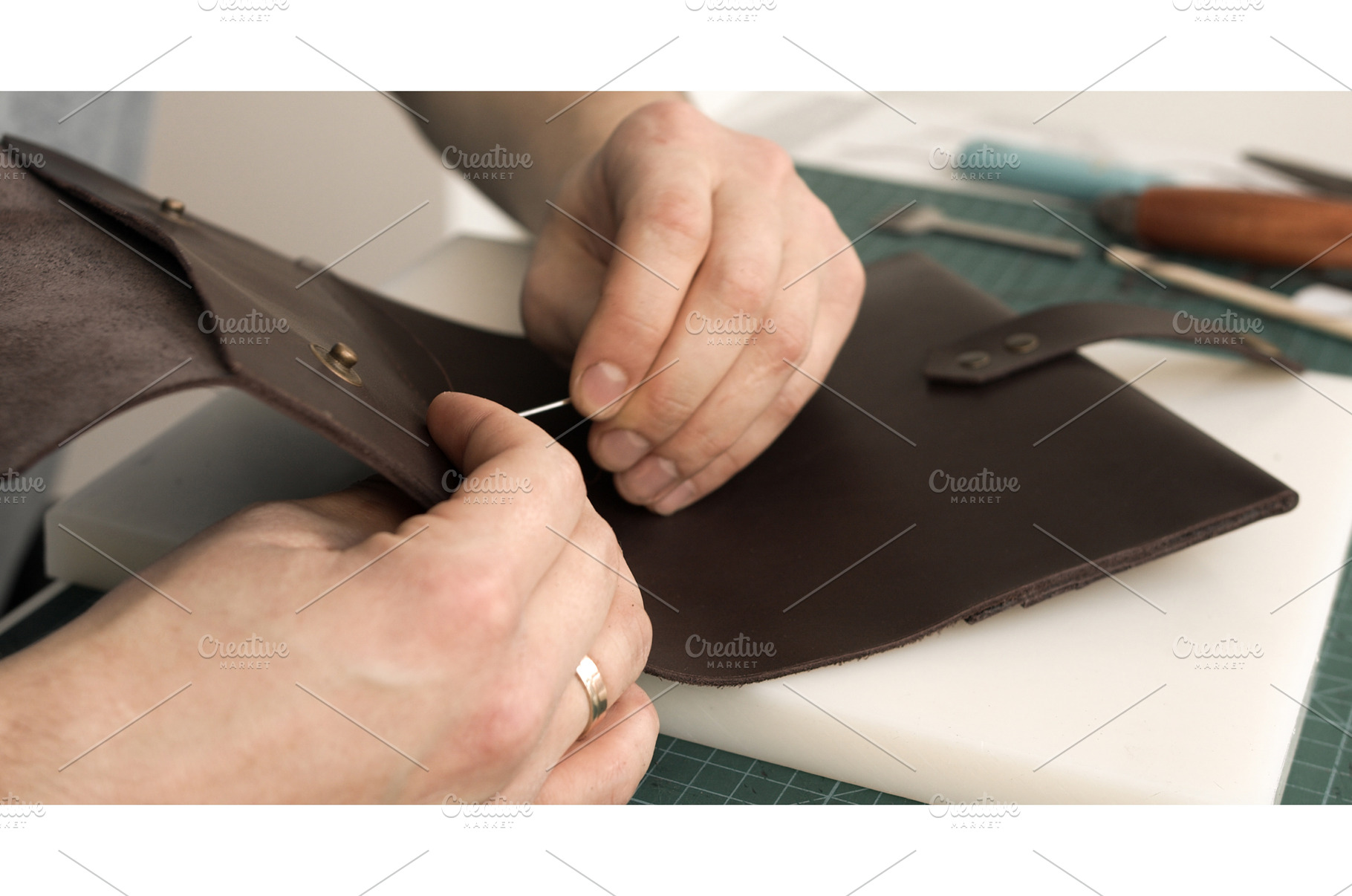 Craftsman hand-stitching strap to, a Person Photo by volodymyrshtun13795