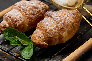 Baked croissants sprinkled with powdered sugar on a metal rack,, a Food & Drink Photo by ndanko