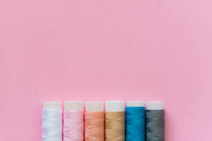 Thread spools with pink background containing thread, spool, and embroidery