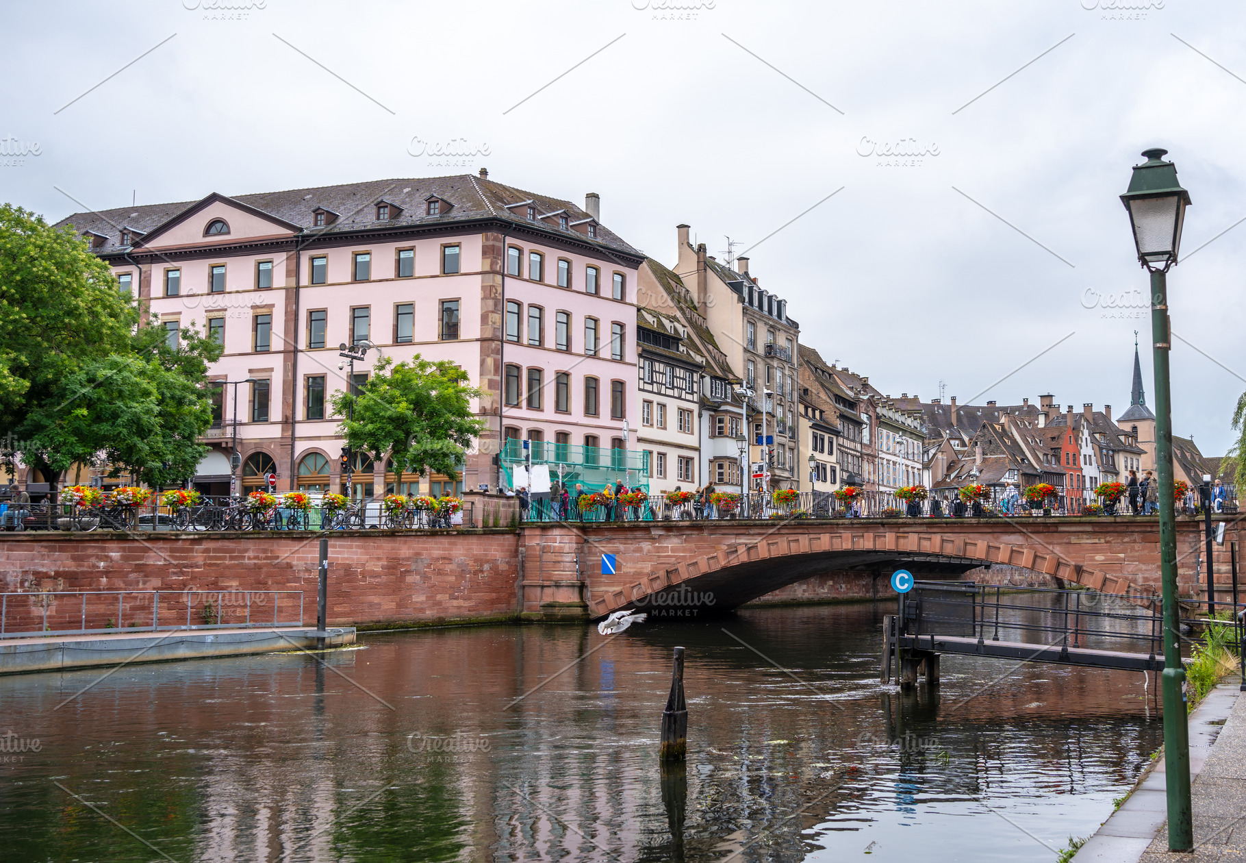 Bridge with flowers over the Ill river in Strasbourg, France, an Architecture Photo by GoodGoods