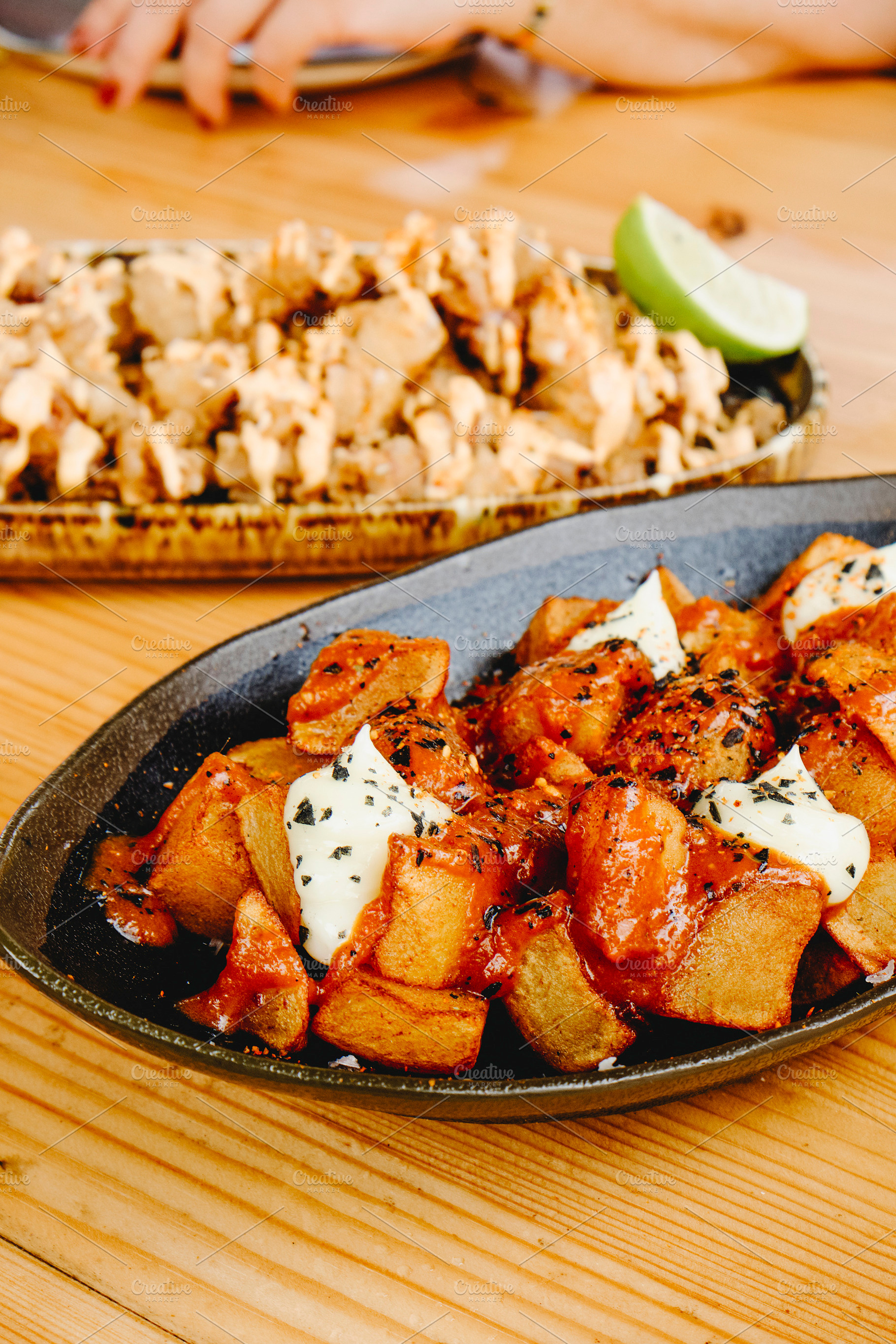 patatas bravas and chipirones on wooden table, a Photo by Nito