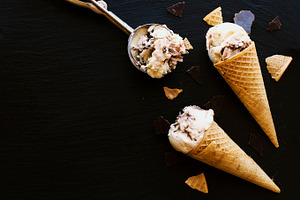 Chocolate ice cream in a sugar waffle cones containing ice, cream, and scoop