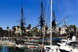 Historic wooden ships docked alongside modern yachts in scenic Barcelona, Catal, a Photo by AS photostudio