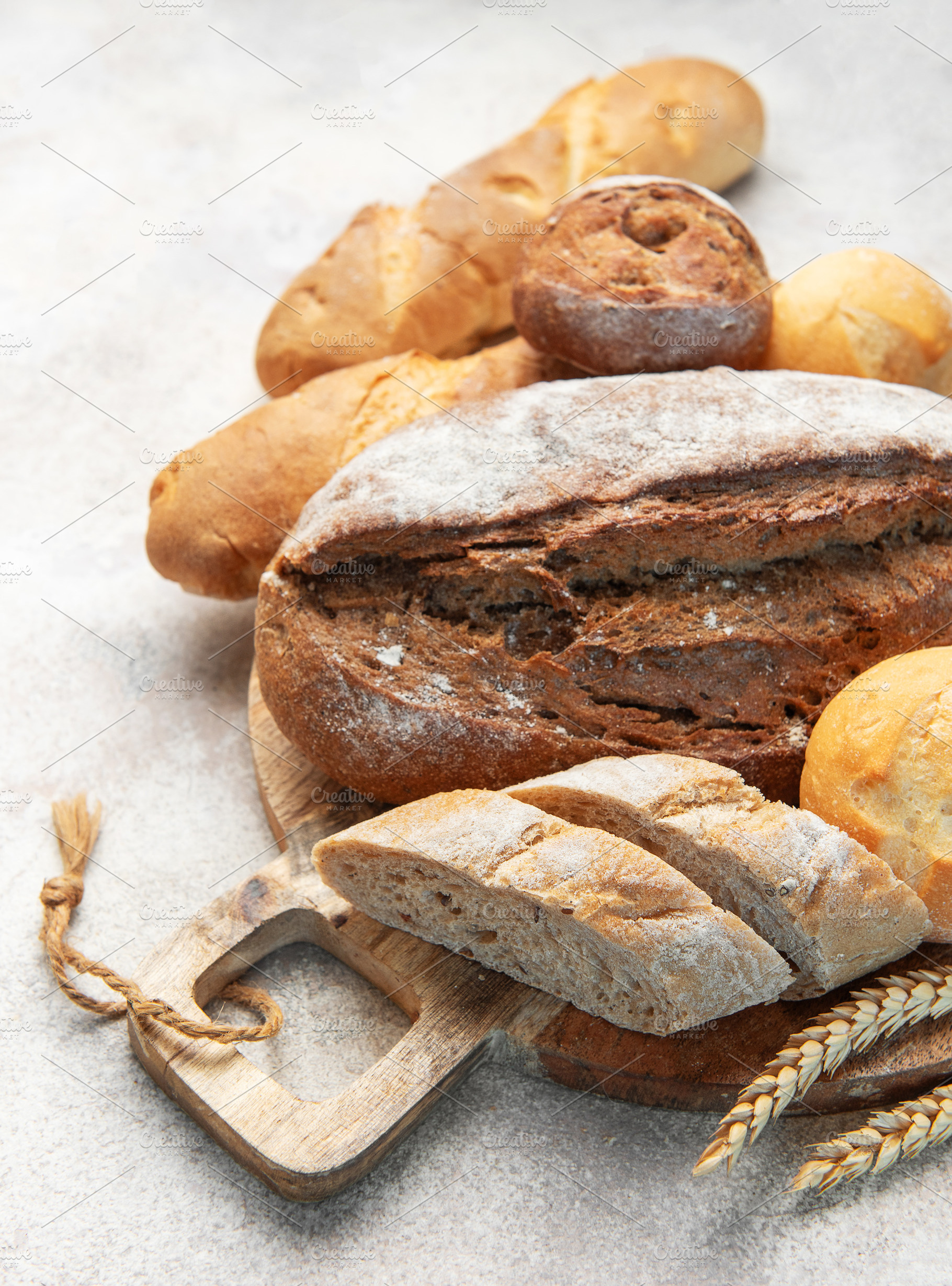 Assortment of fresh baked bread on rustic wooden board, a Food & Drink Photo by Olena Rudo