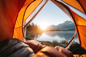 Opening tent door reveals stunning lake view at sunrise in mountainous wilderne, a Photo by AlyaAnd