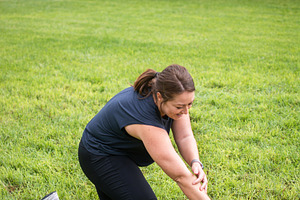 Woman stretching her leg on grass during outdoor fitness workout