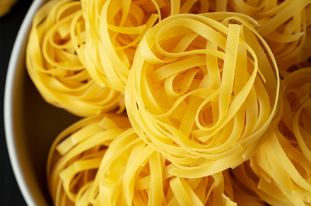 Raw Dry Tagliatelle Pasta in a Bowl, top view., a Food & Drink Photo by LiudmylaChuhunova