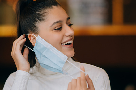 Girl in takes off her protective medical face mask
