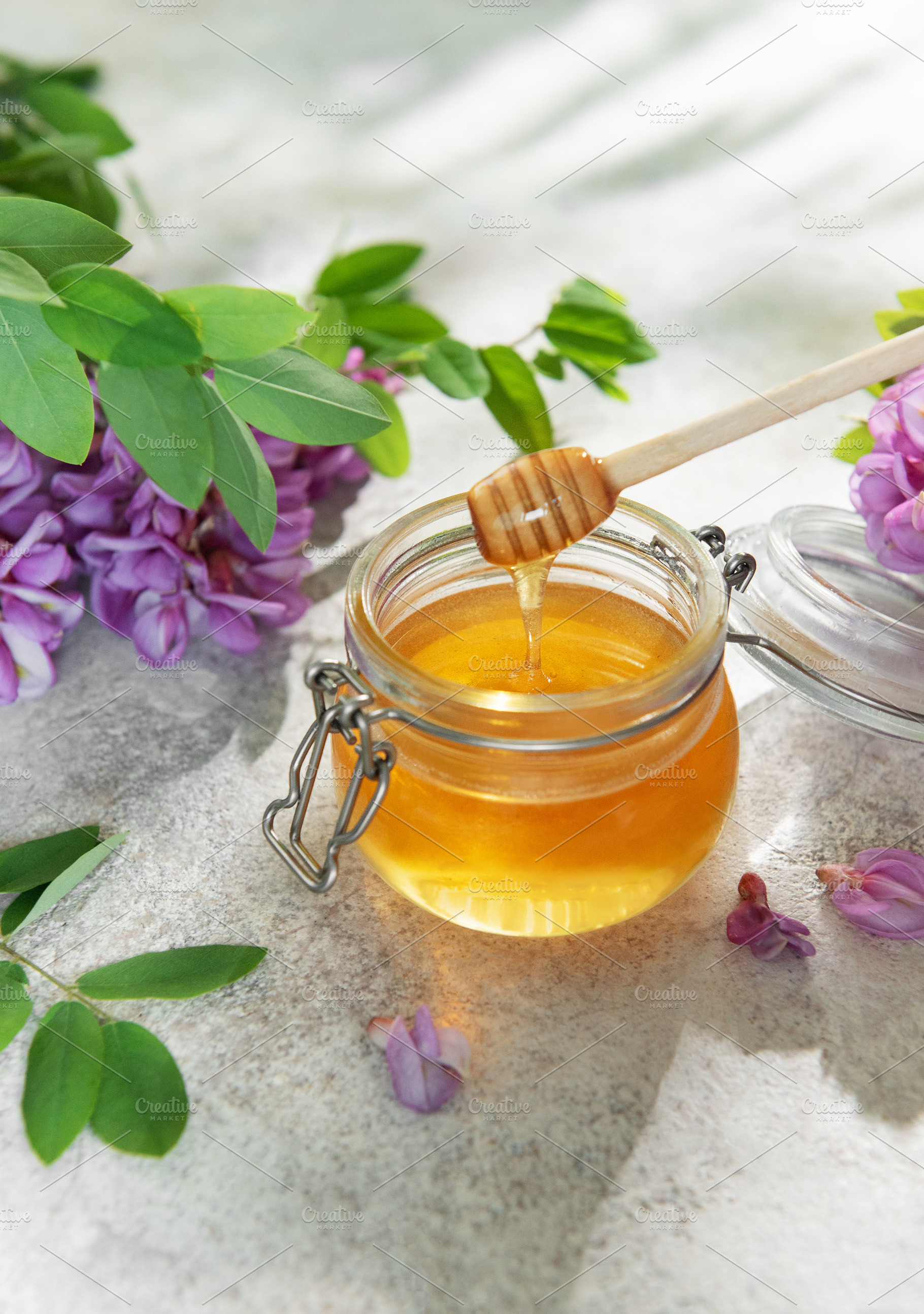 Acacia honey in glass jar with wooden dipper, a Food & Drink Photo by Olena Rudo