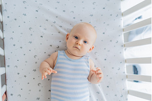 Baby lying peacefully in a cozy crib, a Person Photo by Elizaveta Galitskaya