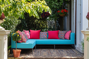 Outdoor turquoise sectional sofa with pink and multicolor cushio, a Photo by Studio ANNA