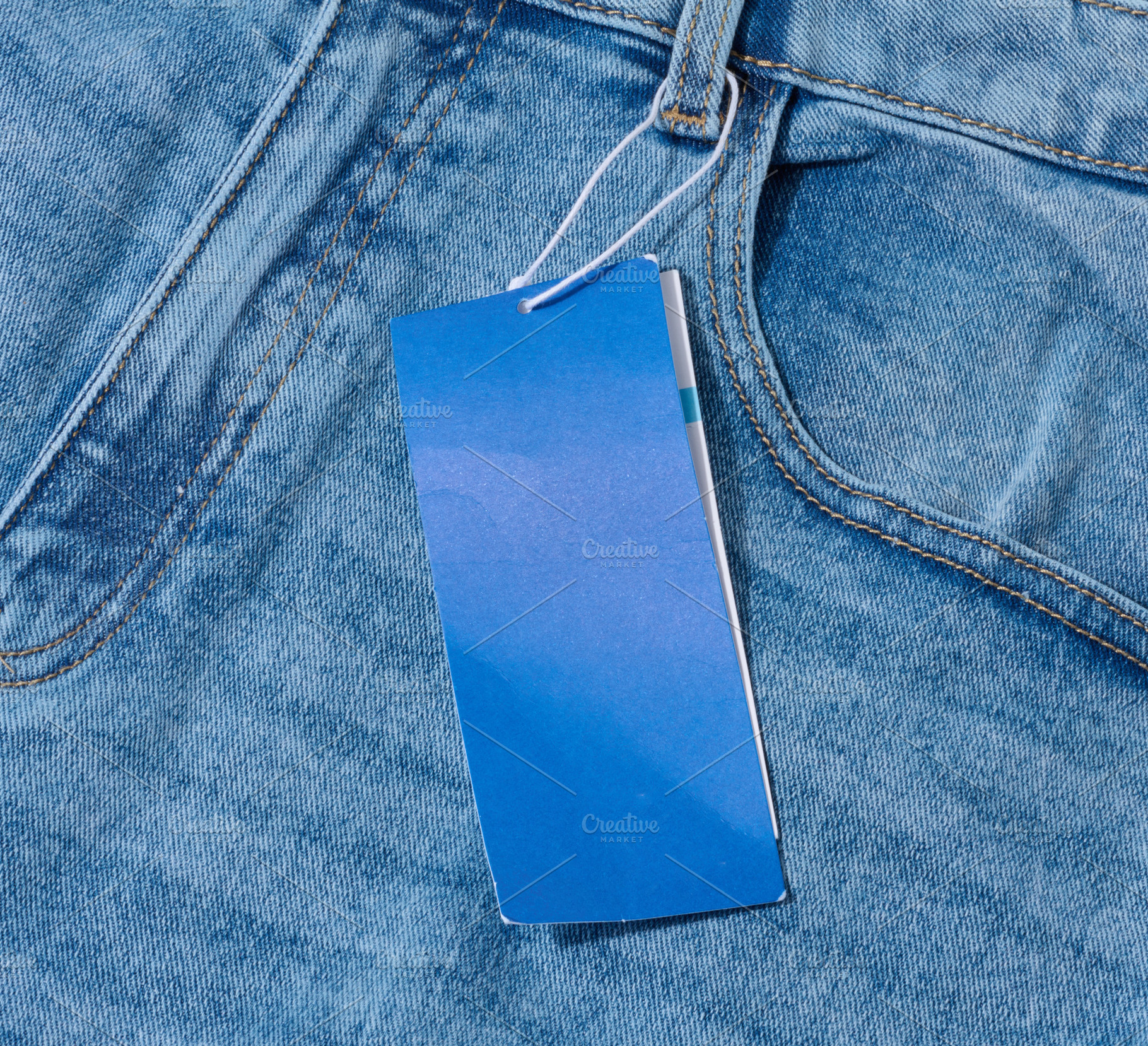 Close-up of light blue denim jeans with a blank blue price tag a, a Beauty & Fashion Photo by ndanko