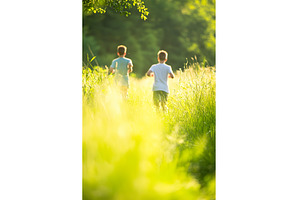 Two boys running through sunlit, a Person Photo by Lermont51