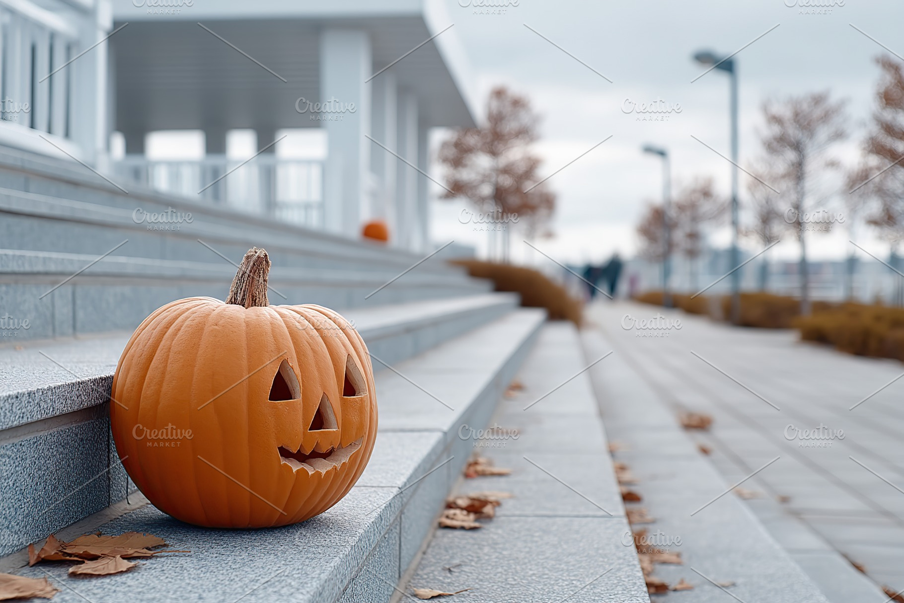 Carved pumpkin on steps in urban park during autumn with people walking in back, a Holiday Photo by AlyaAnd