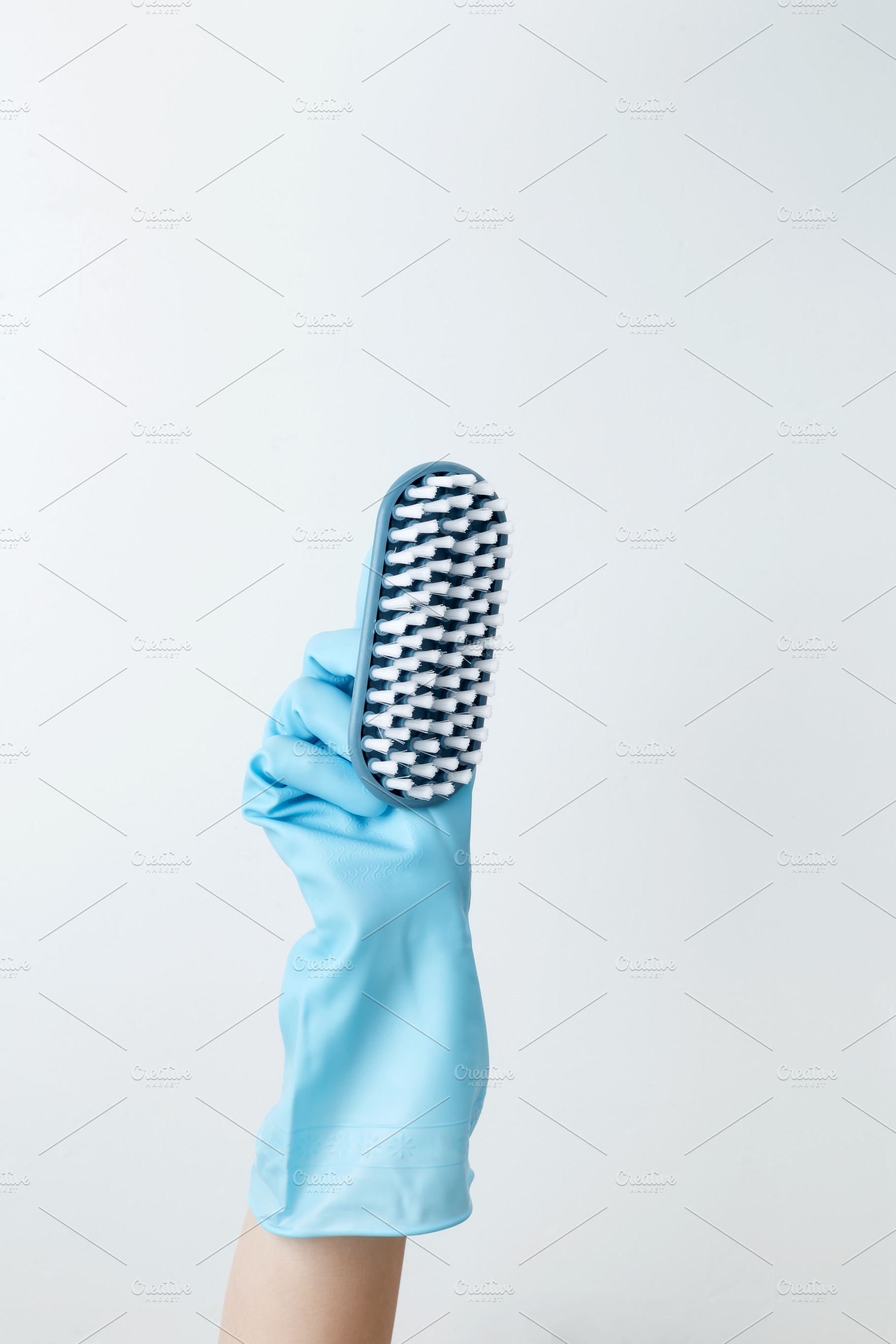 A hand in a blue rubber glove holding a cleaning brush, focused on cleaning tas, a Photo by matucha