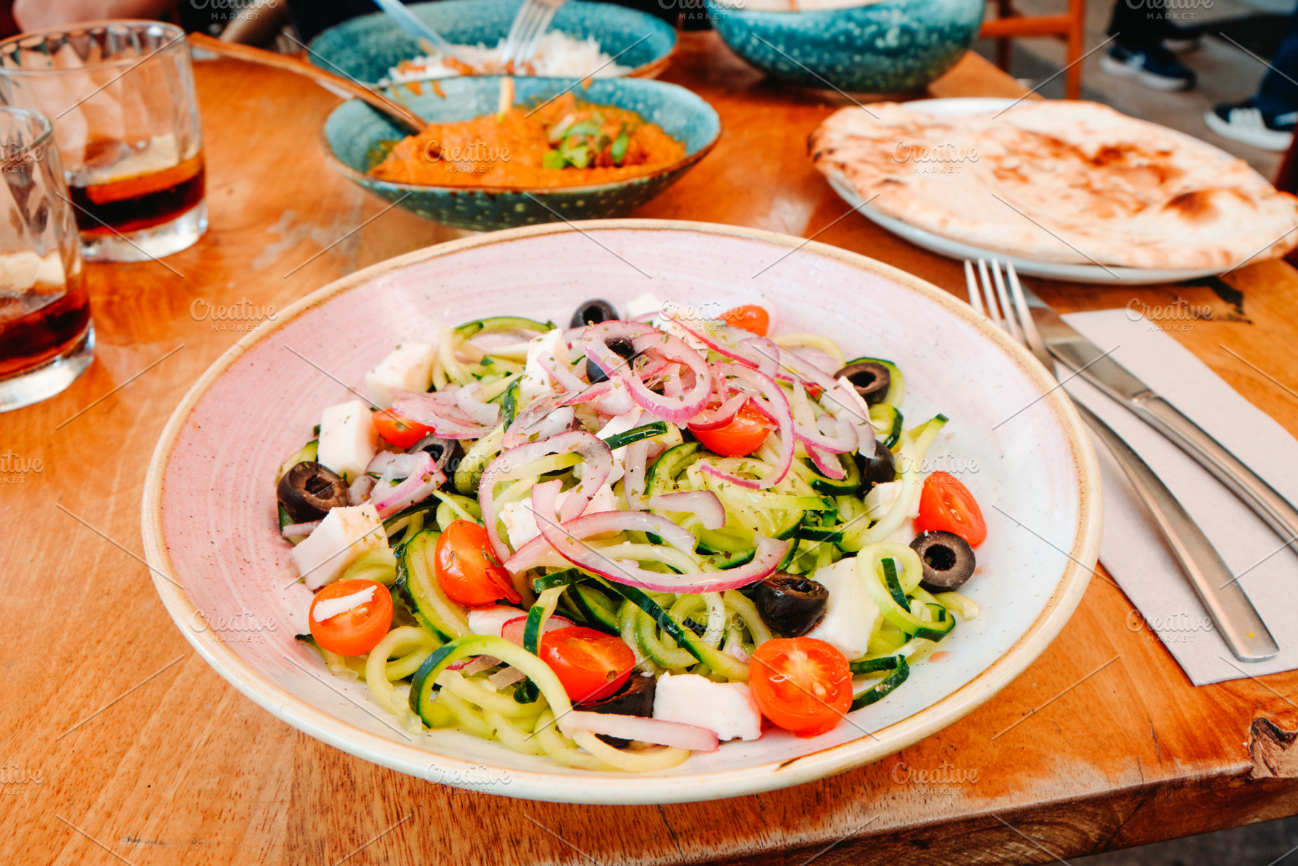 a fresh cucumber salad served at a restaurant table, a Photo by Nito