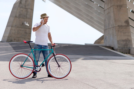 young man using his cellphone while going to work with his bicycle