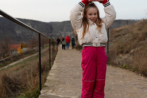 Cheerful young girl in warm clothing poses on a stone path with, a Person Photo by Ales Munt