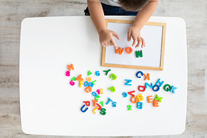 Early development and preparation for school. Top view of little kid making wor, a Photo by Prostock-Studio