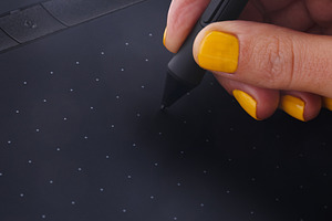 Close-up of a hand with yellow nails using a stylus on a digital, a Technology Photo by Ales Munt