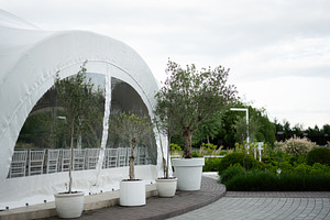 Elegant outdoor setting with white marquee and lush green plants, a Photo by AS photostudio