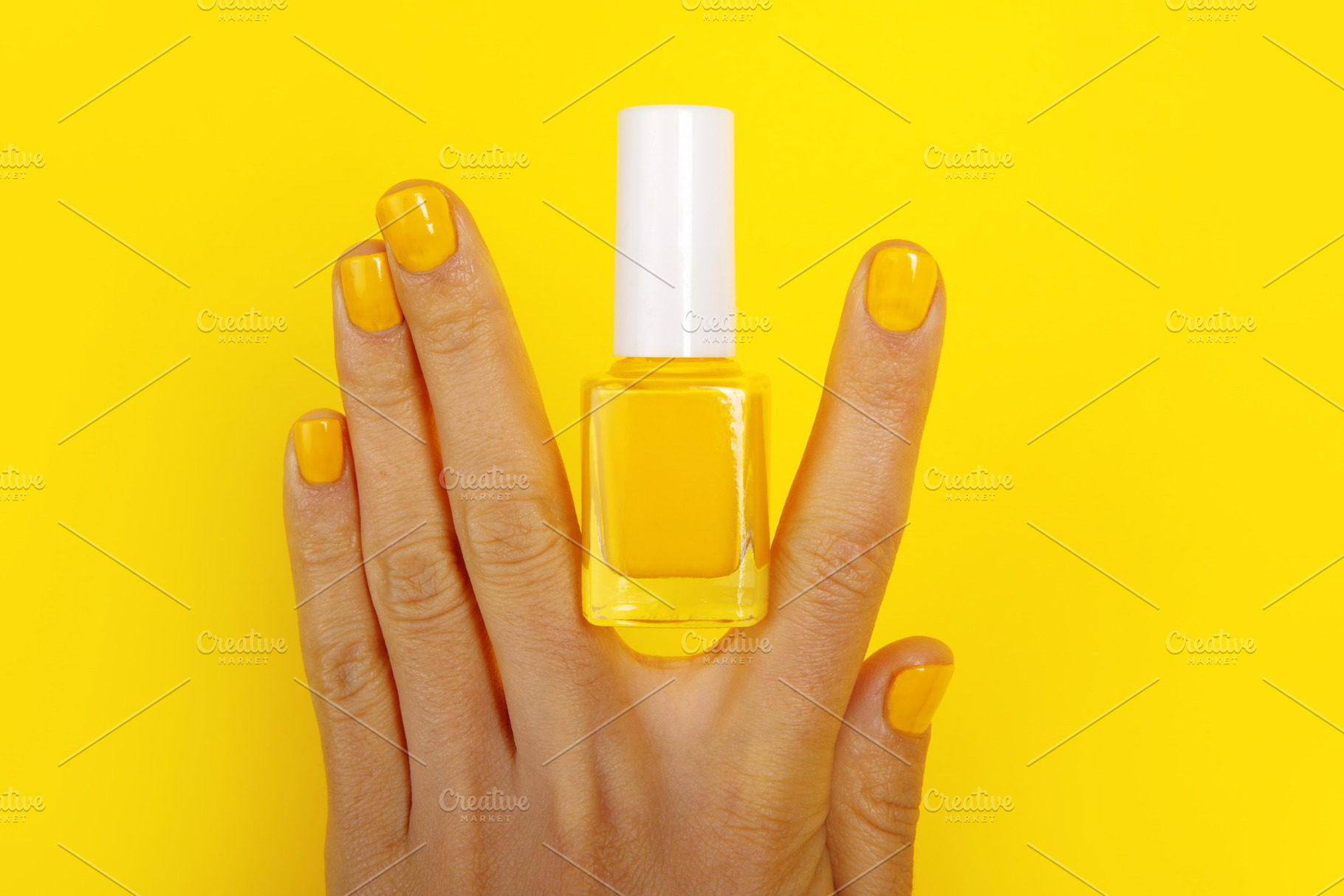 Hand with manicured yellow nails and matching nail polish bottle, a Beauty & Fashion Photo by Ales Munt