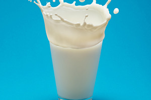 Milk splash (crown) on a glass of milk isolated on blue backgrou, a Food & Drink Photo by Volff