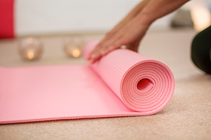 Hands winding the pink yoga mat