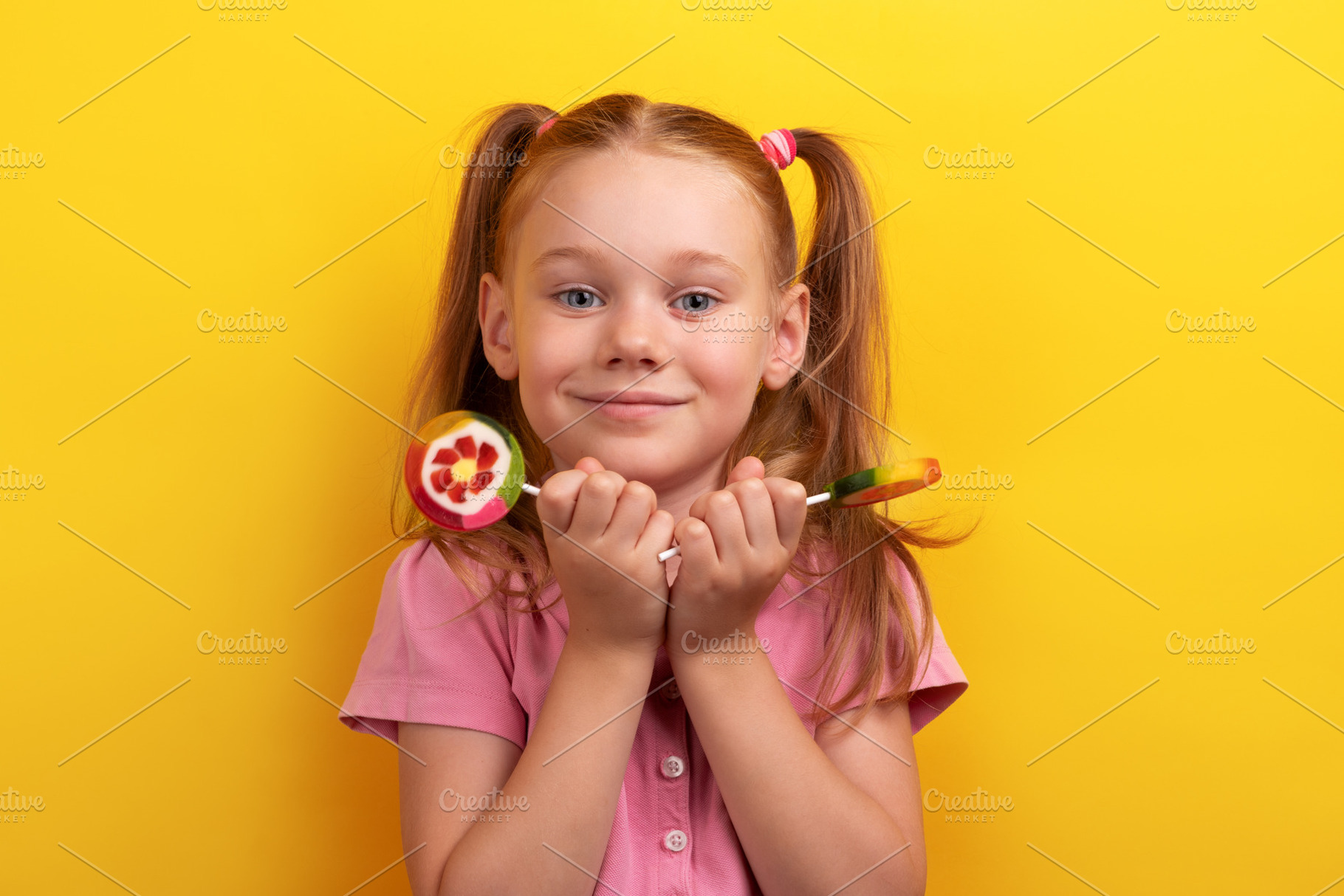 Smiling young girl in pink shirt holding colorful fruit lollipop, a Person Photo by Ales Munt