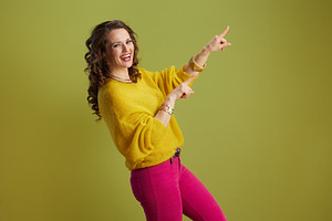 smiling modern woman pointing isolated on green, a Person Photo by Alliance Images
