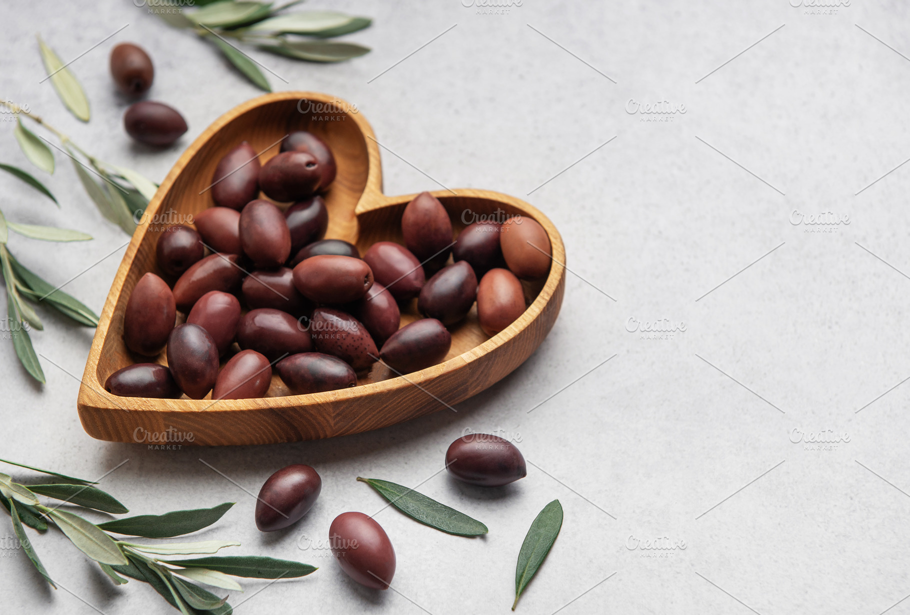 Heart shaped wooden bowl with fresh olives displayed, a Food & Drink Photo by Olena Rudo