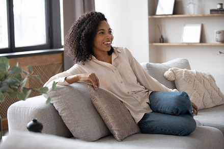 mixed race woman sitting on sofa, a Person Photo by OPOLJA