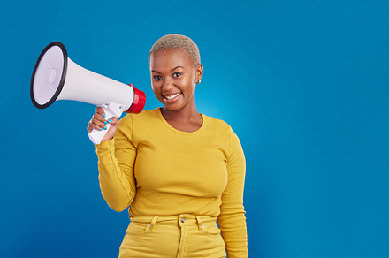 Black woman, megaphone and portrait, protest and voice, freedom of speech and activism on blue background. Female smile, broadcast and speak out, rally and mockup, loudspeaker with opinion in studio, a Photo by Peopleimages.com
